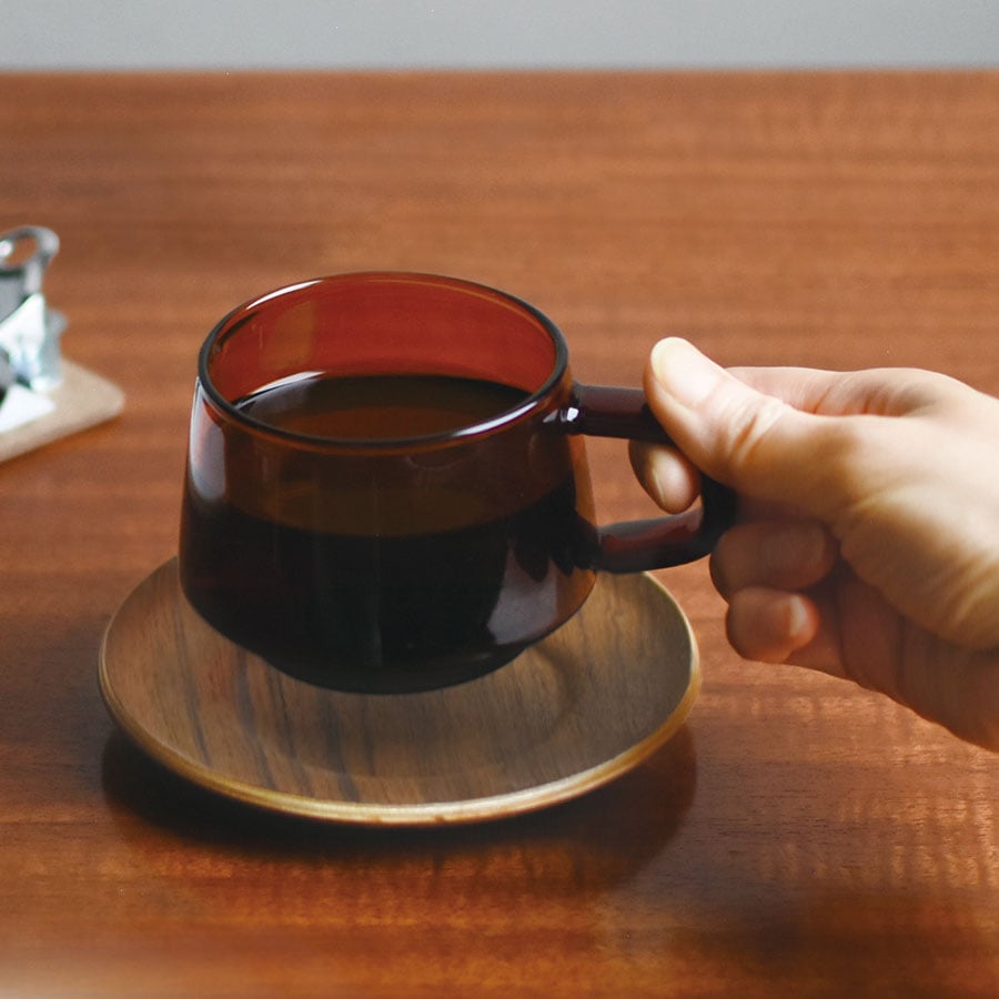 Hand holding a cup of coffee on a wooden table