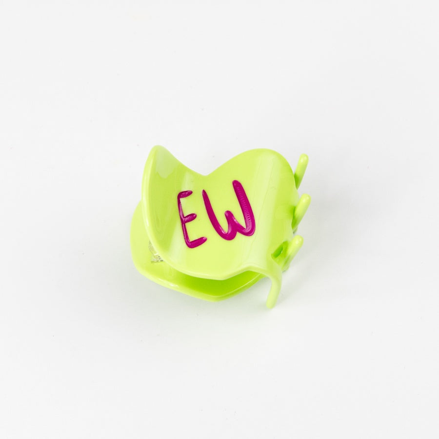 Green heart-shaped hair claw with 'EW' written on it against a white background