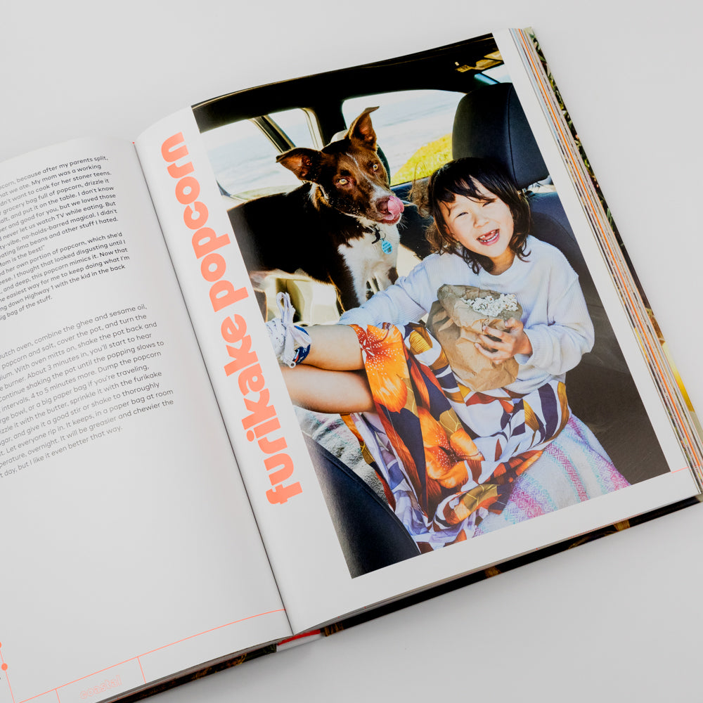 Open book with a photo of a child and dog on a car seat, featuring the title 'Furikake Popcorn'.