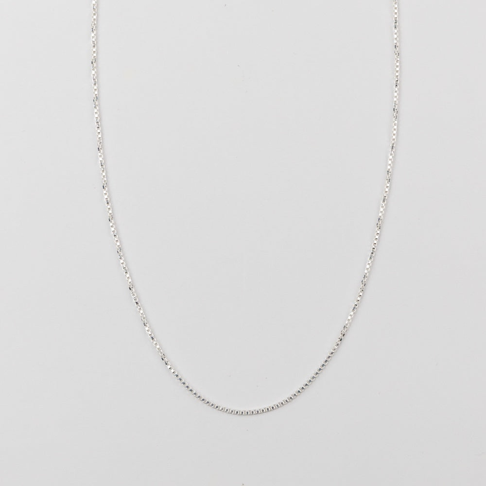 Silver chain necklace on a light gray background