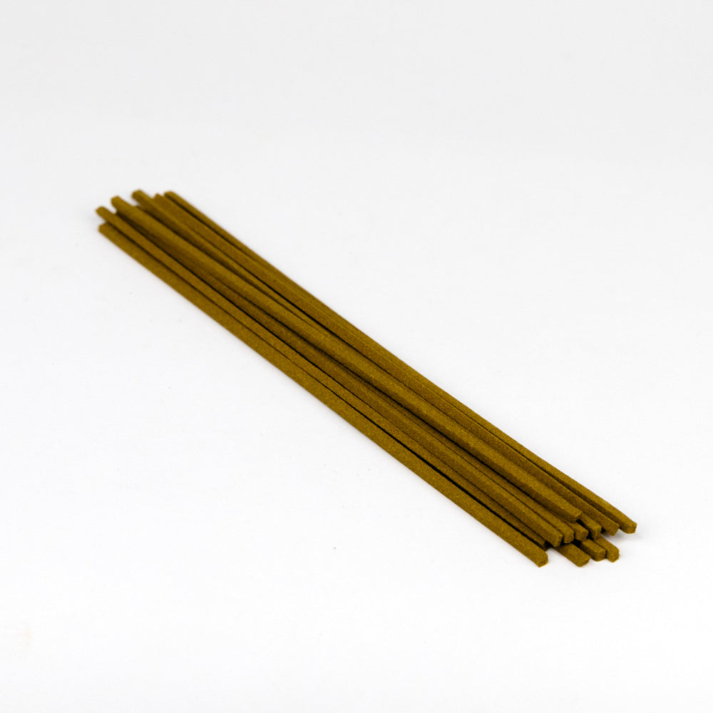 Set of six gold-colored incense sticks on a white background
