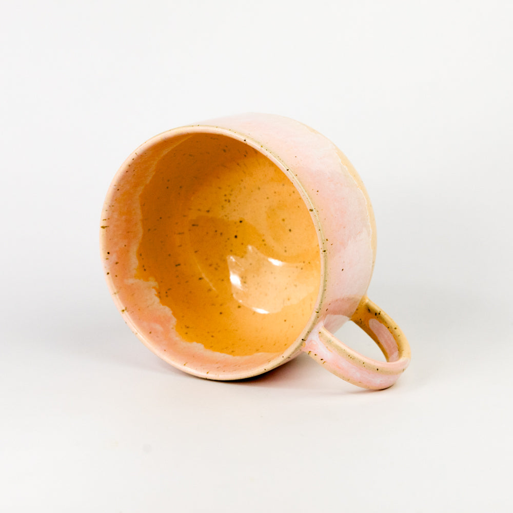 Pink ceramic mug with a speckled texture on a white background