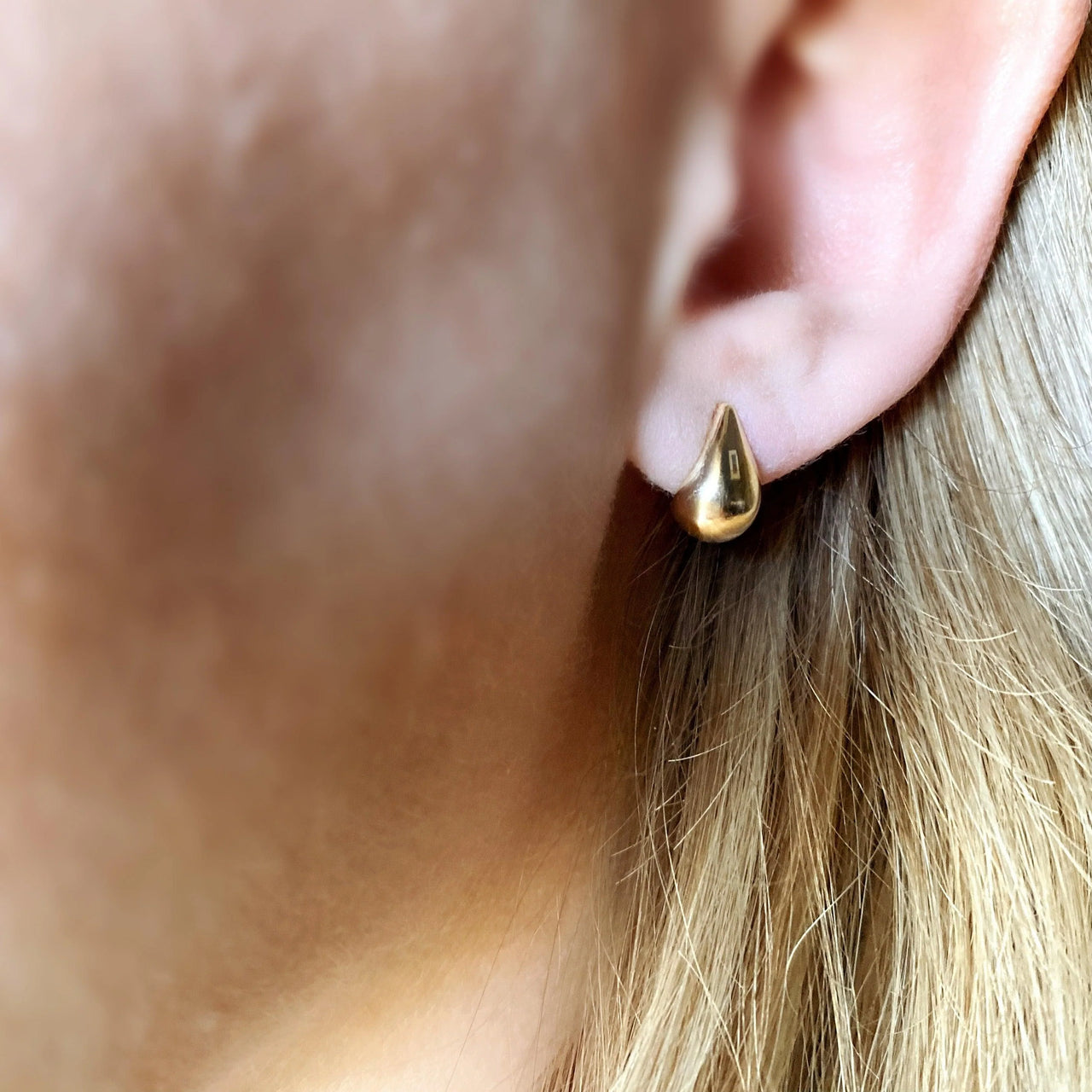 Gold earrings on a light gray background