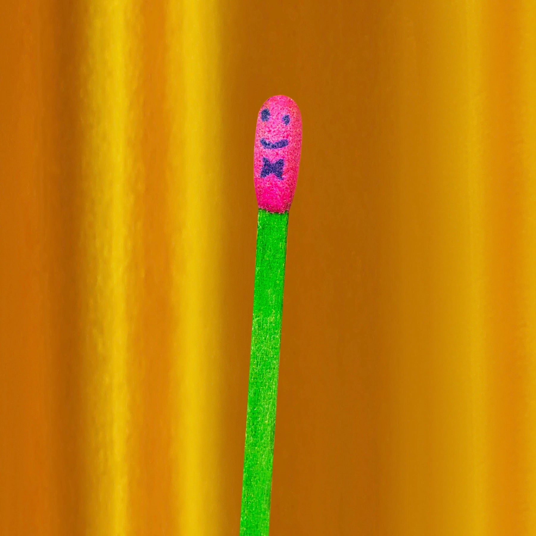 Matchstick with a pink head and blue face on an orange background
