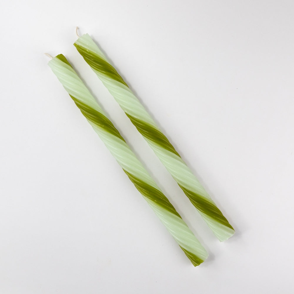 Two green and white striped candles on a light gray background