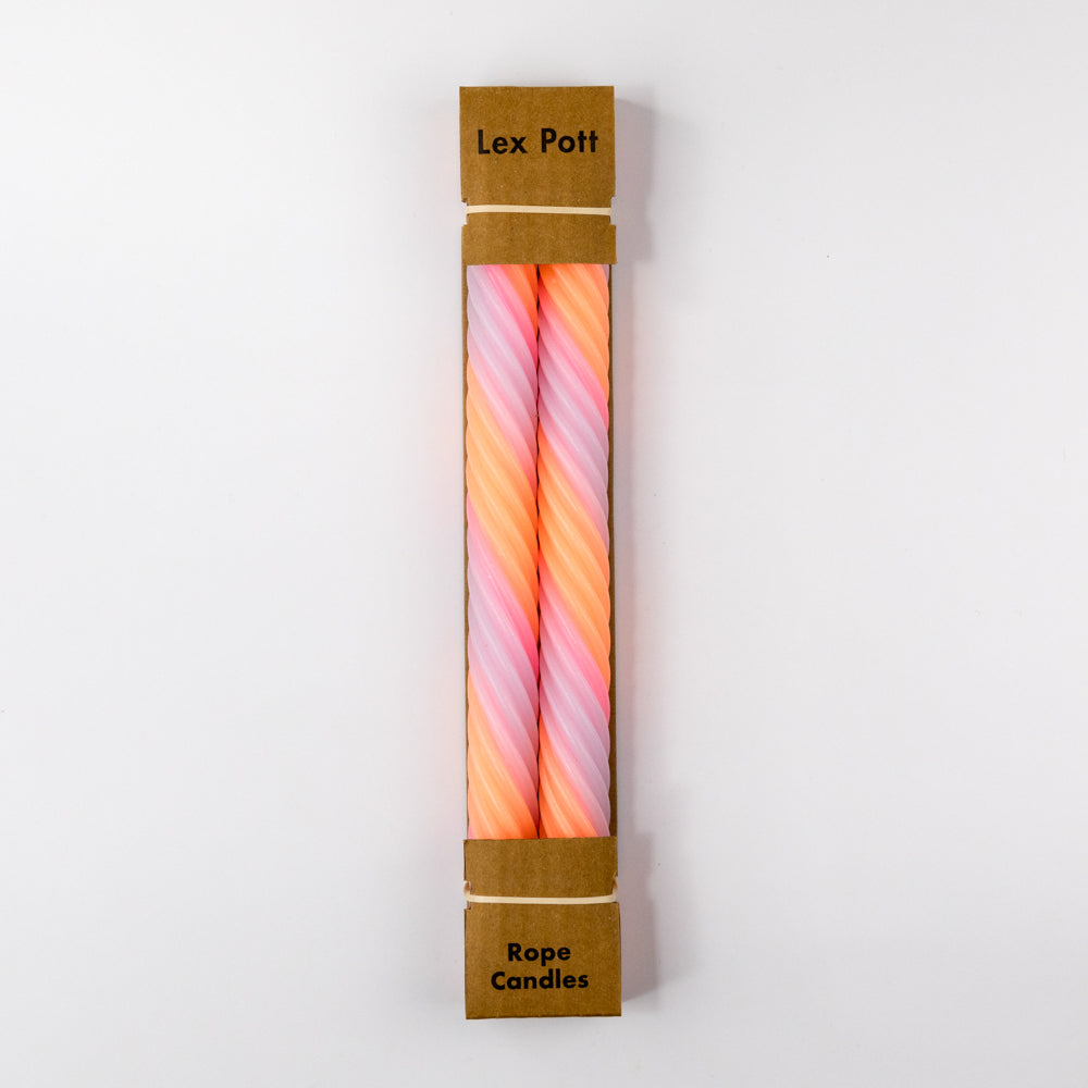 Three spiral-shaped candles in pink, orange, and white on a light gray background