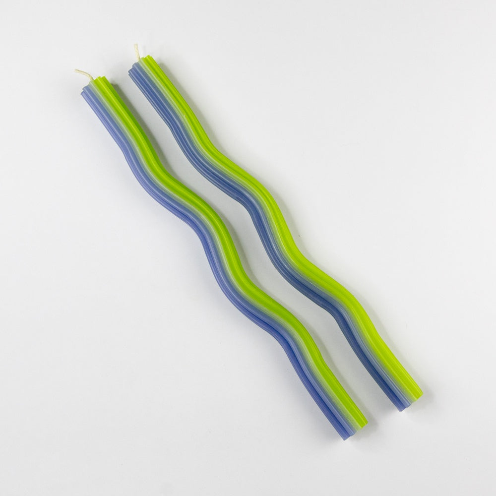 A pair of wavy candles with blue and green stripes on a white background