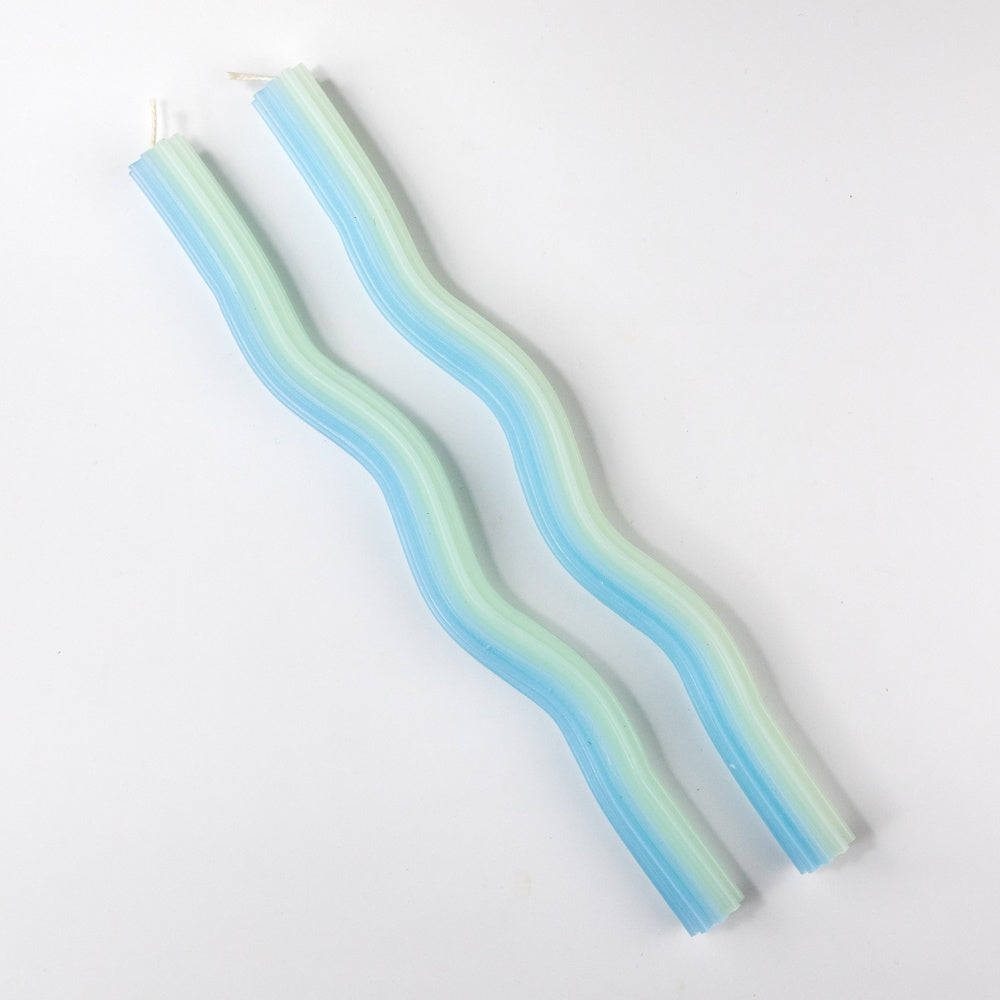 Two green and blue striped candles on a white background