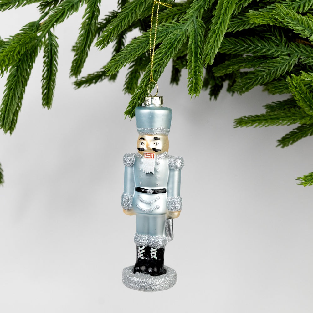 Decorative nutcracker ornament hanging on a Christmas tree branch.
