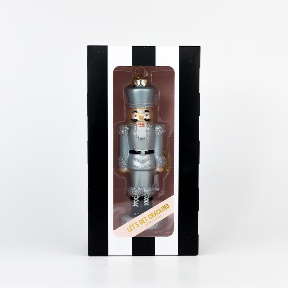 Silver nutcracker ornament in packaging on a white background