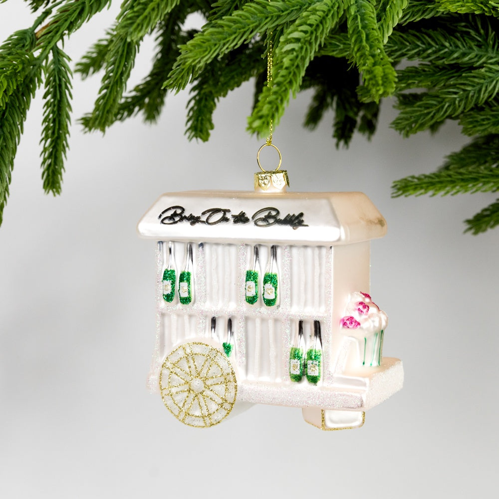 Decorative Christmas ornament resembling a vintage ice cream cart with champagne bottles on a white background.