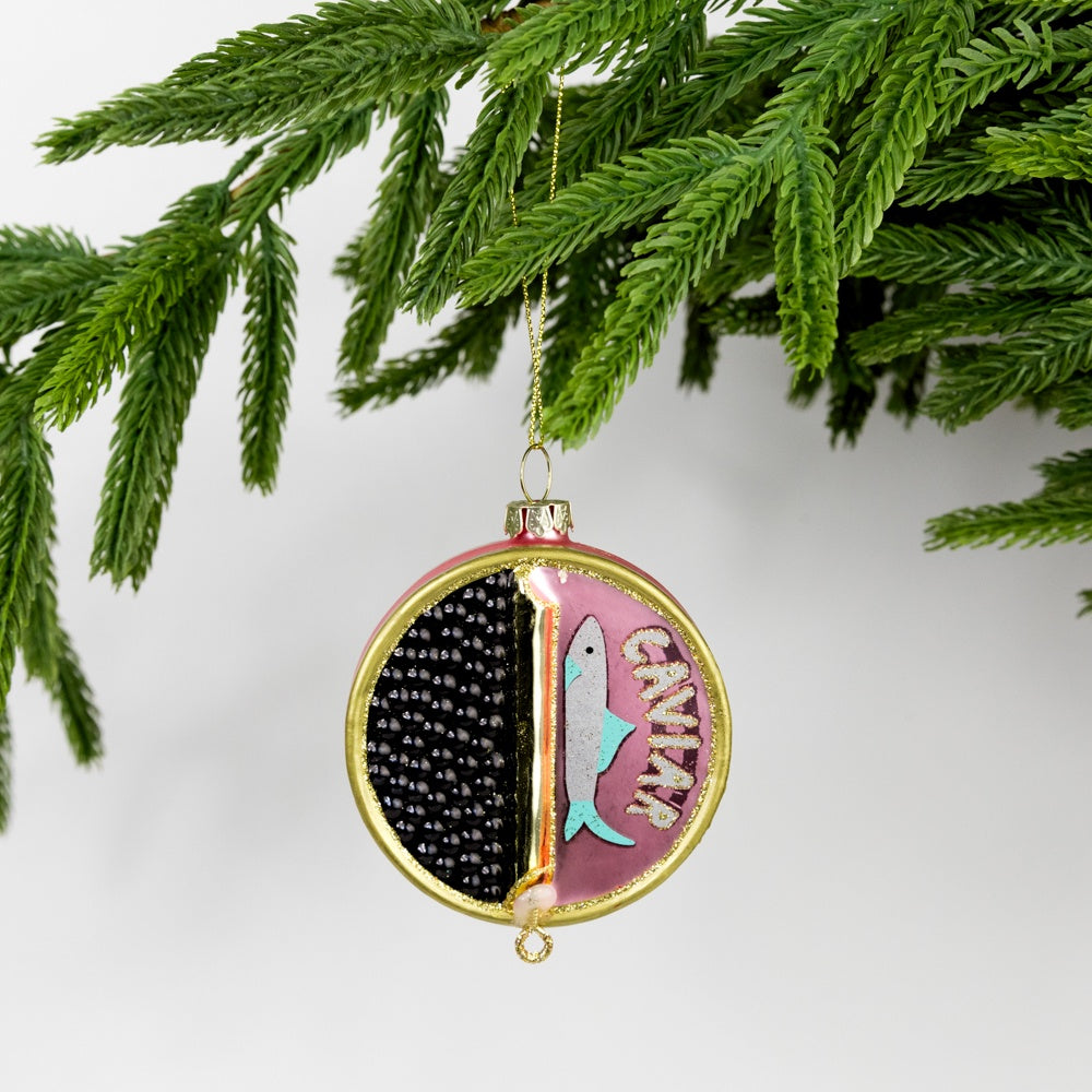 Decorative Christmas ornament shaped as a partially open can of caviar hanging on a tree branch.