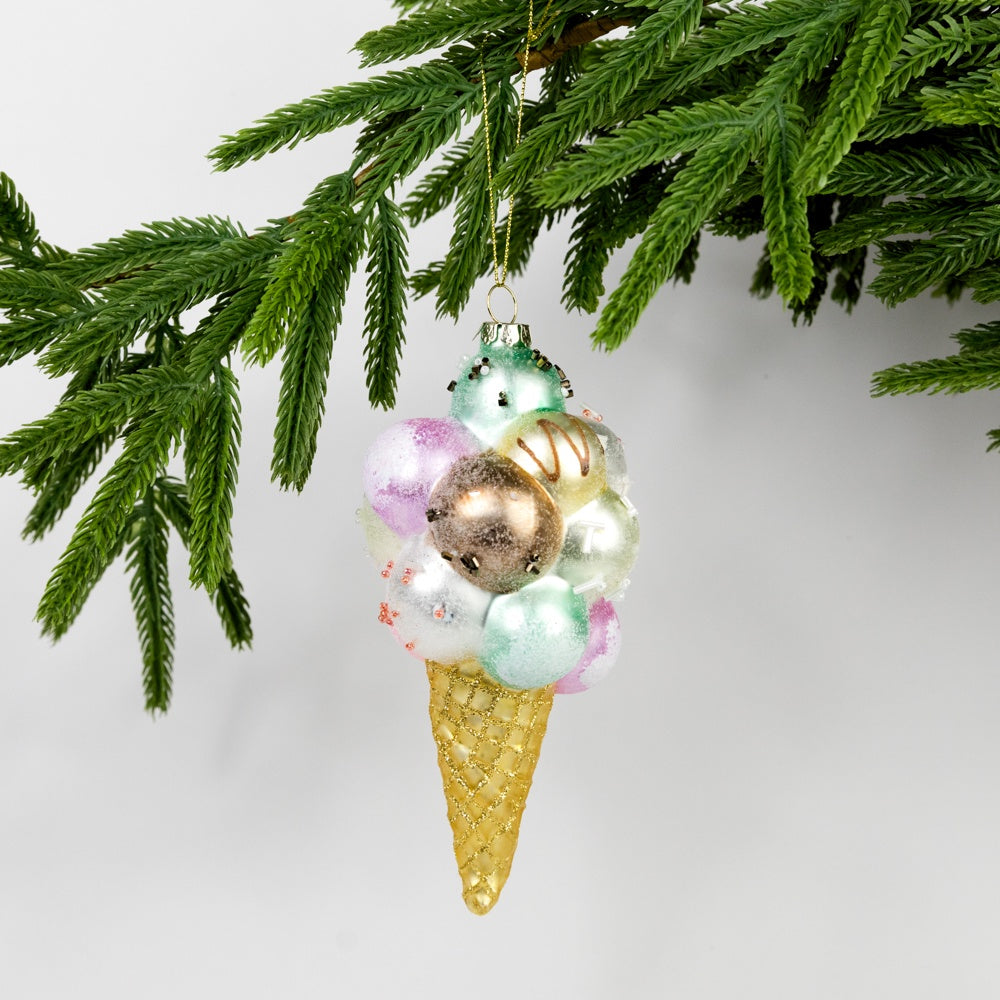 Decorative ice cream cone ornament with colorful scoops hanging from a tree branch.