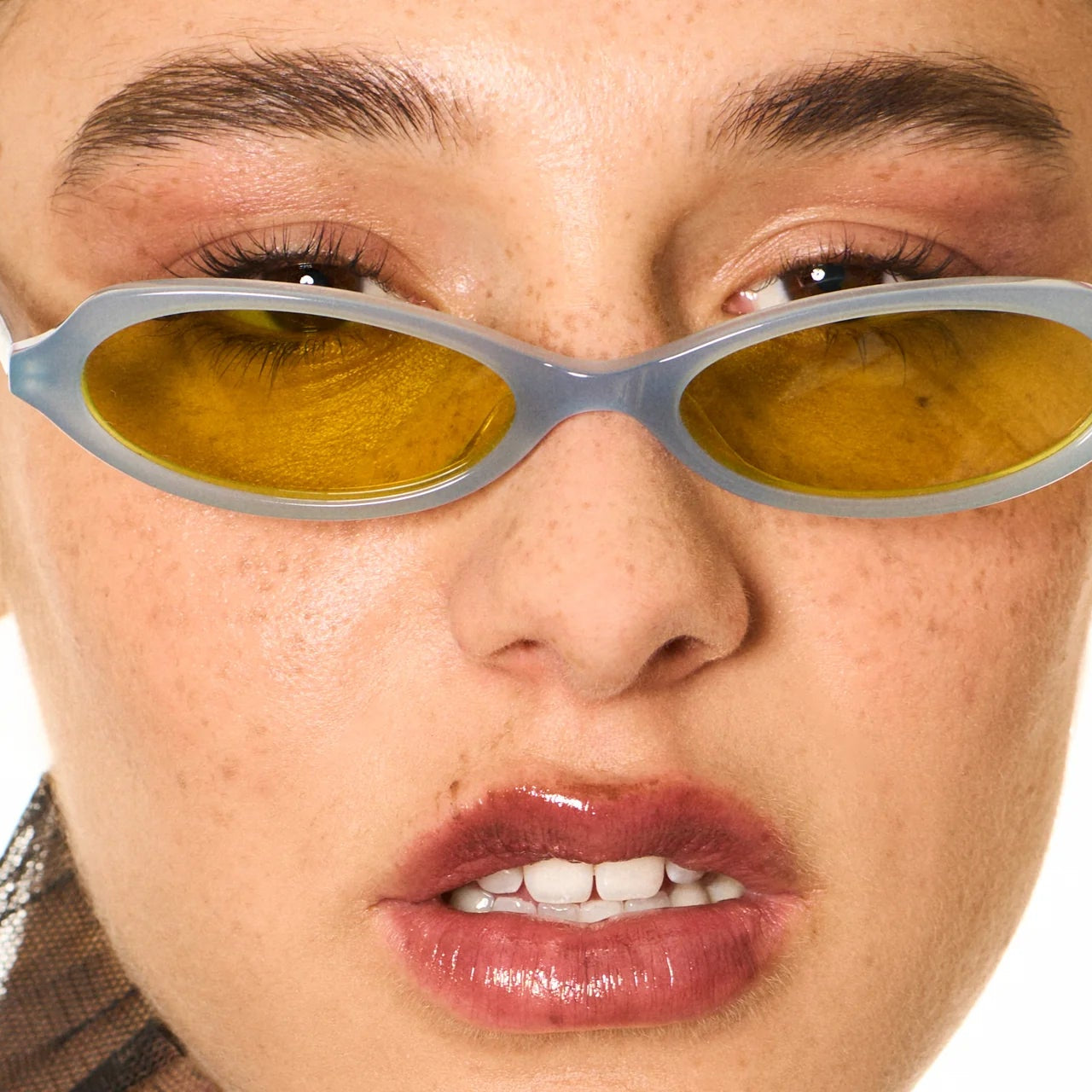 Close-up of a person wearing reflective sunglasses with a neutral background