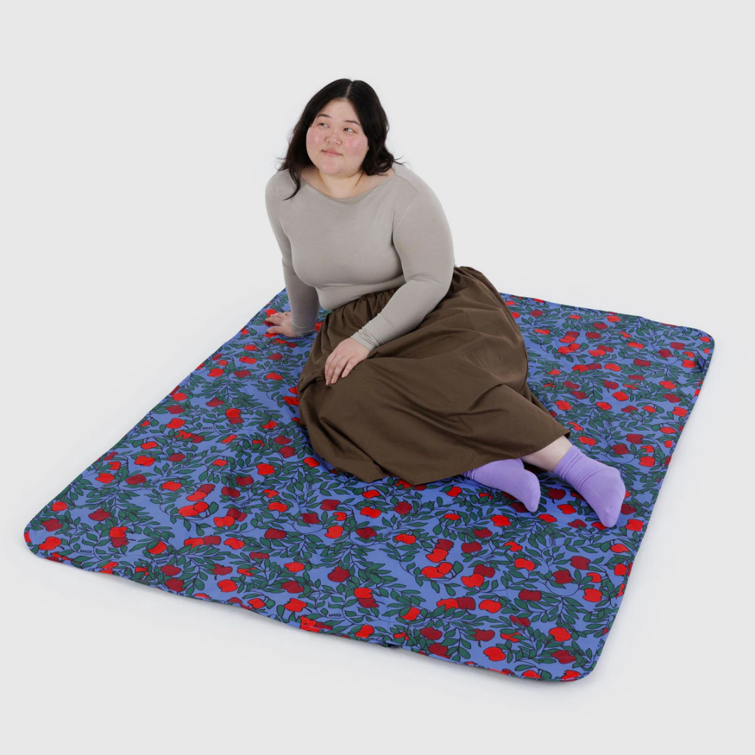 Person sitting on a floral-patterned blanket with a white background