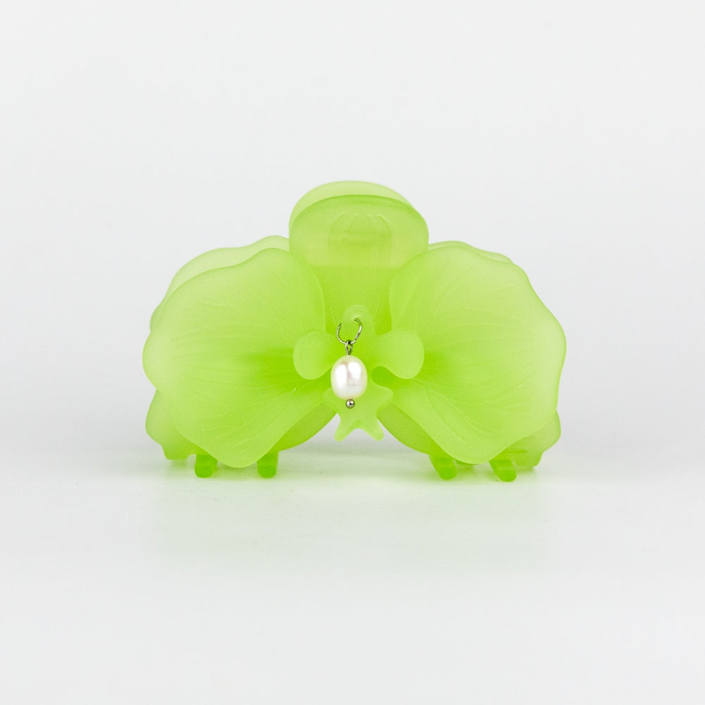 Green orchid-shaped hair clip with a pearl on a white background