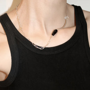 Necklace with a black pendant worn by a person in a black tank top against a neutral background