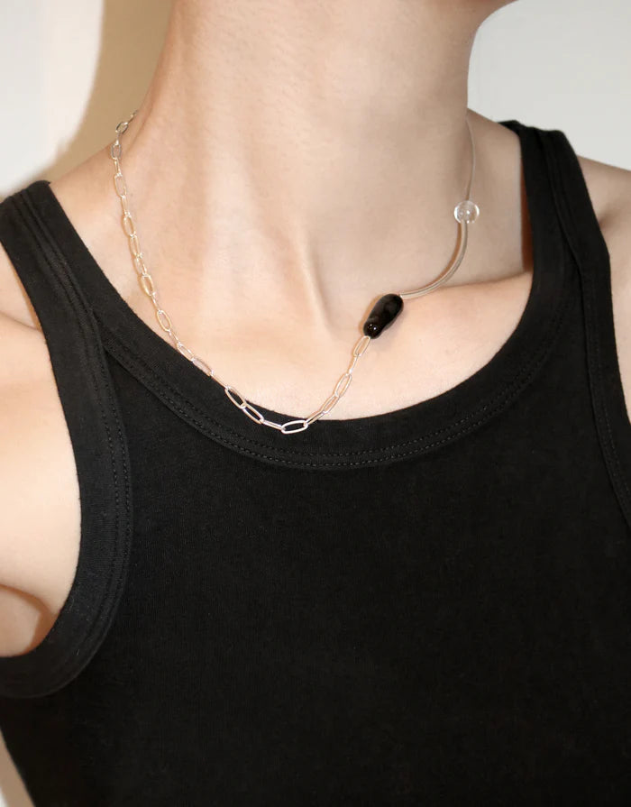 Silver necklace with a black pendant on a white background