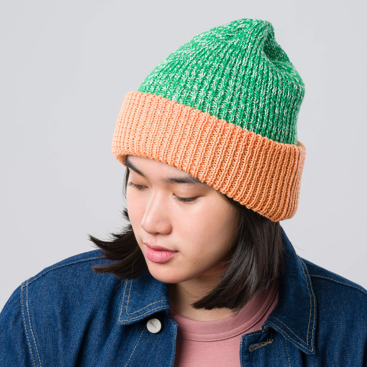 Green and orange knit beanie on a light gray background