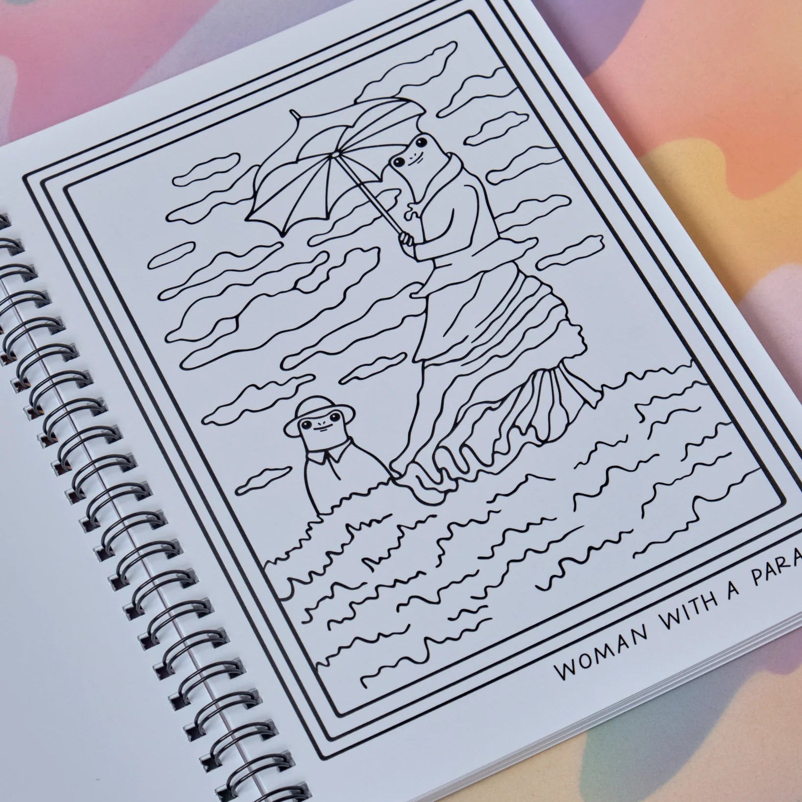 Spiral-bound notebook with a black and white illustration of a woman with an umbrella on a colorful background
