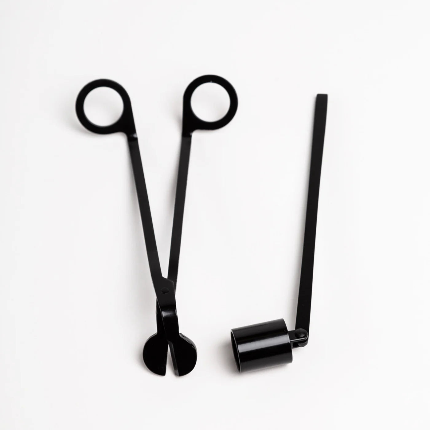 Black scissors and a black cylindrical object on a white background