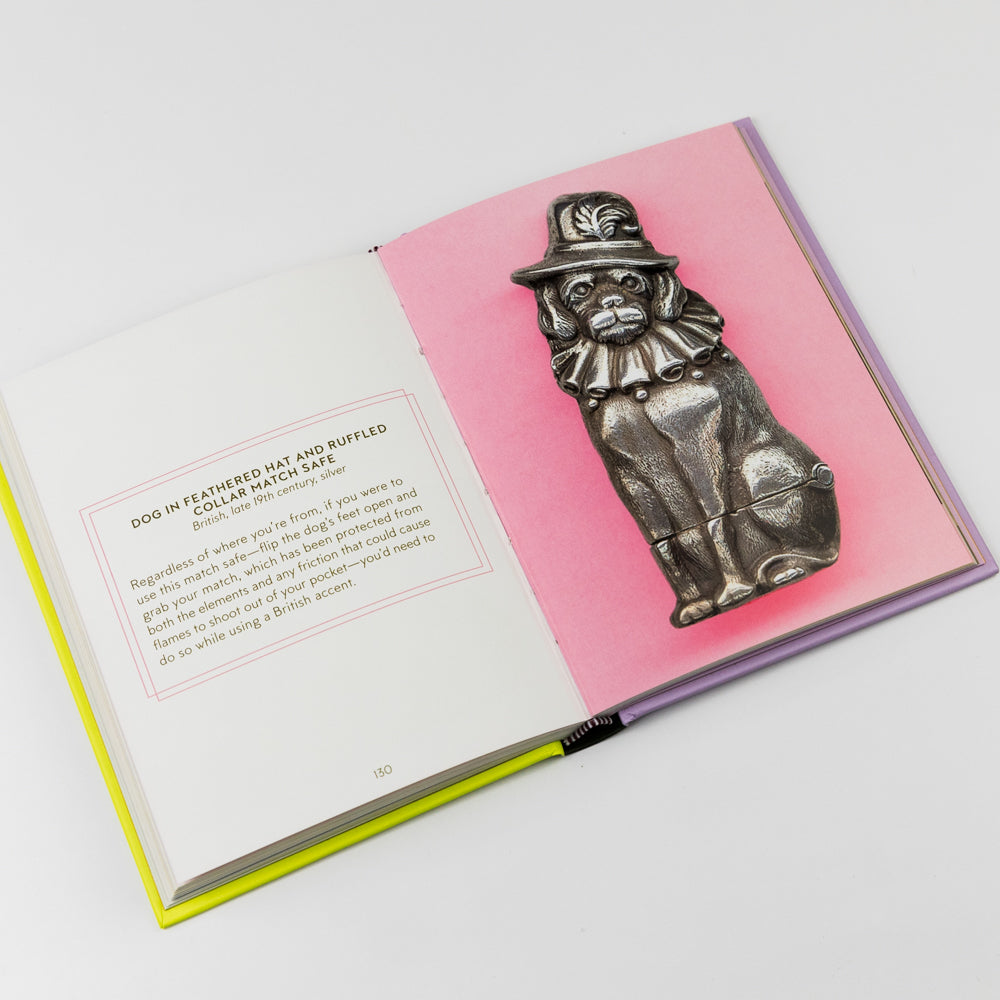 Metallic dog-shaped match safe on a pink card with text, placed on an open book.