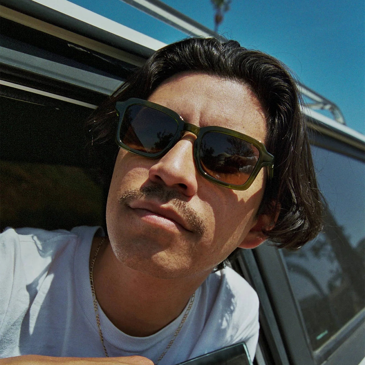 Sunglasses with green frame and brown lenses on a light gray background