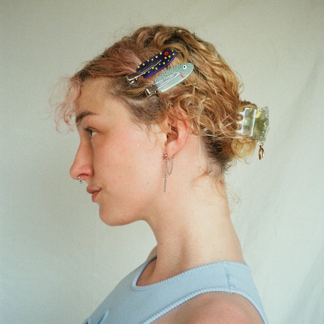 Woman with styled hair featuring colorful hair accessories against a plain background