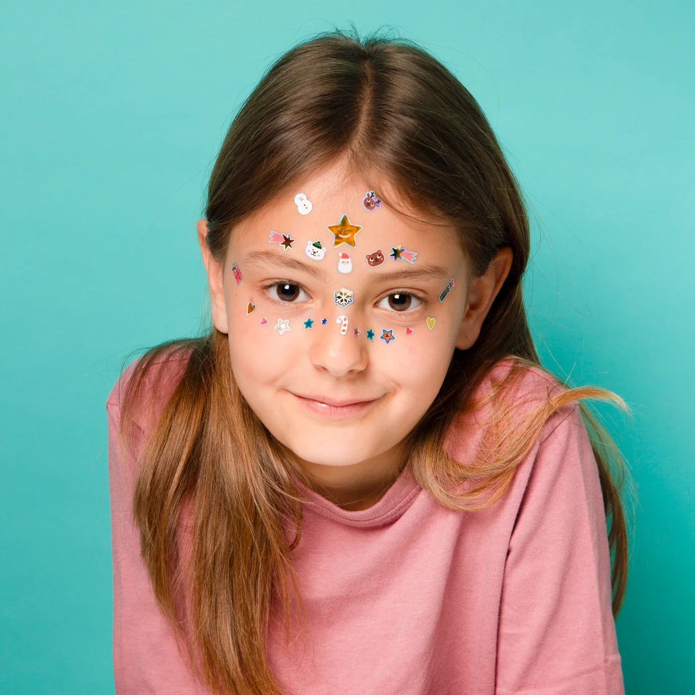 Young girl with face stickers against a teal background