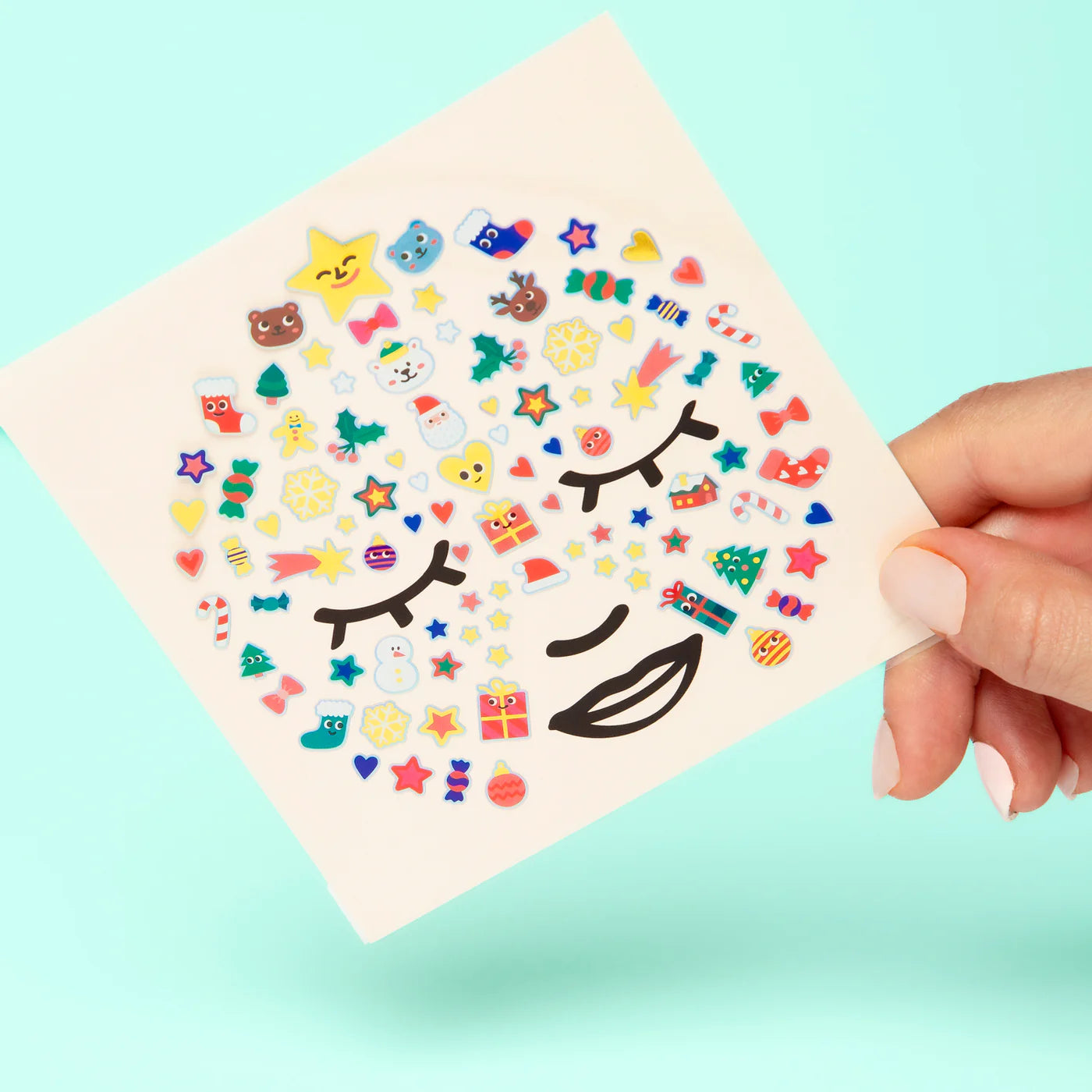 Sheet of colorful face stickers held by a hand against a light blue background
