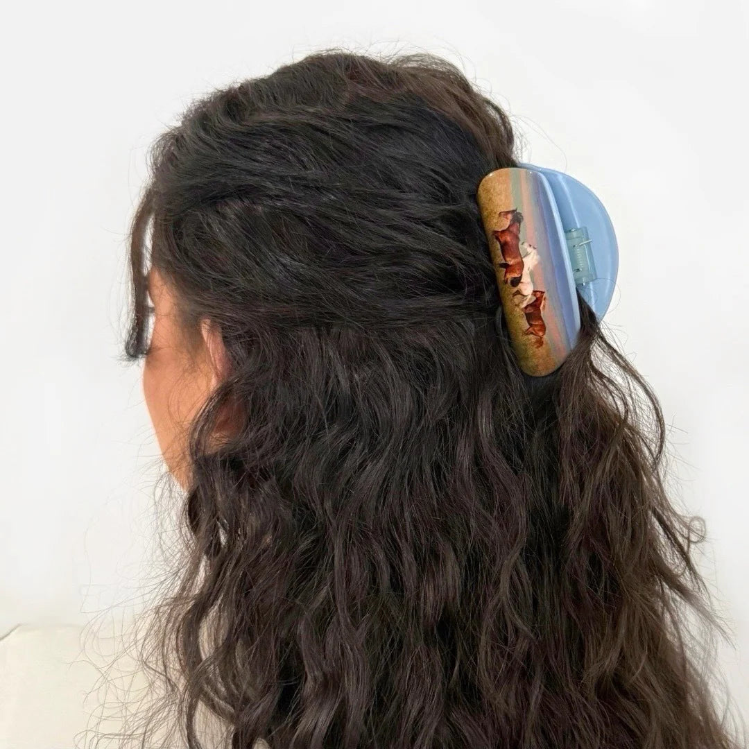 Hair clip with a scenic design of horses on a white background