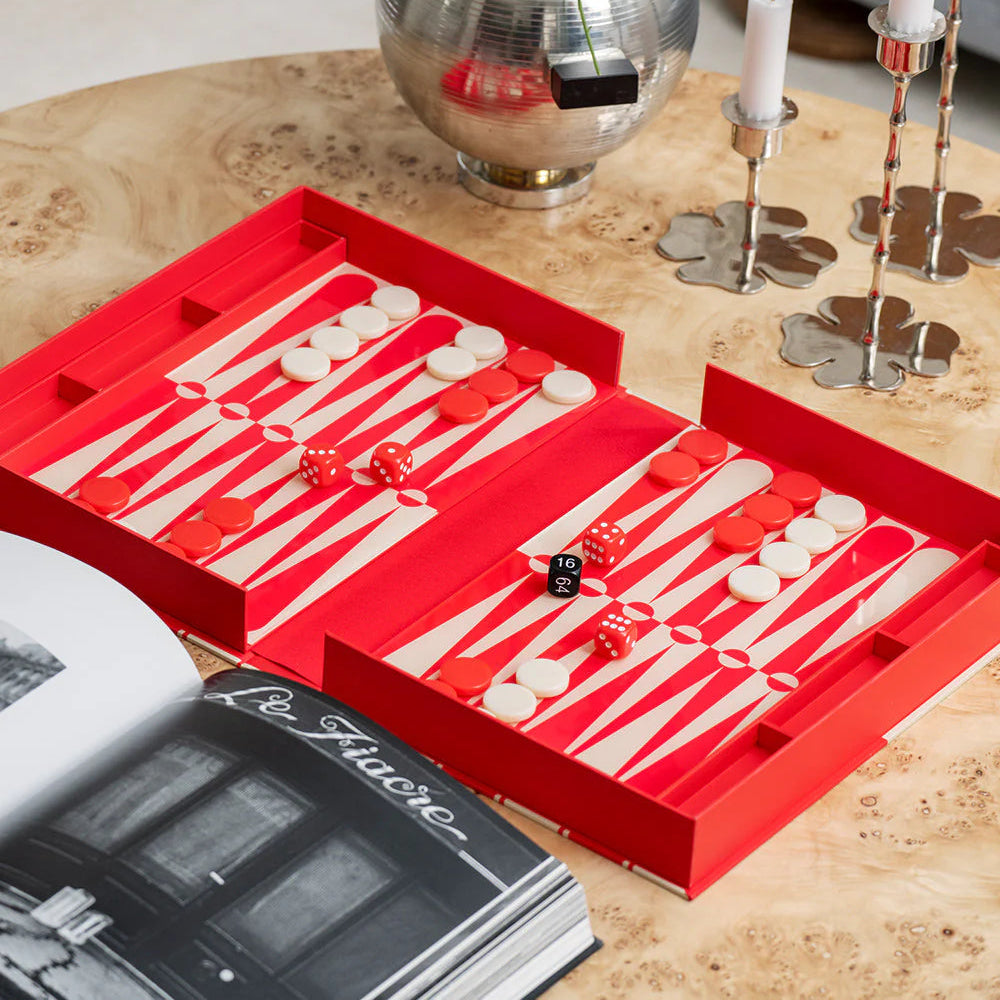 Red backgammon set on a wooden table with decorative items.