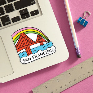 The lower right side of a laptop keyboard with a sticker featuring the Golden Gate Bridge, a rainbow and San Francisco.
