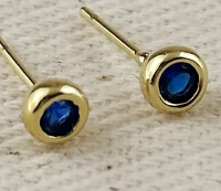 Gold earrings with blue gemstones on a light wooden background