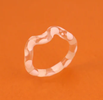 Clear ring with white blotch pattern on an orange background