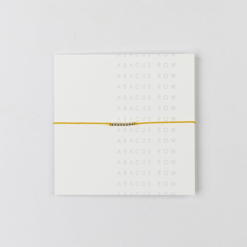 White card with gold text and a yellow bracelet on a white background