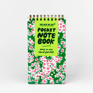 Pocket notebook with floral pattern and green text on a white background