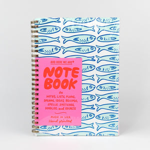 Notebook with blue fish pattern and pink front cover on a white background