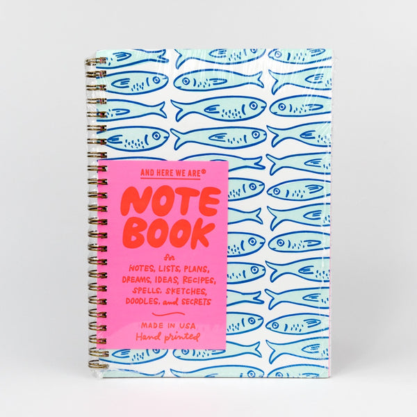 Notebook with blue fish pattern and pink front cover on a white background