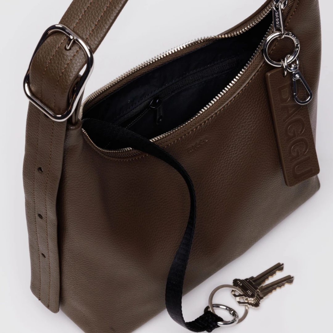 Brown leather handbag with a strap and keys on a white background