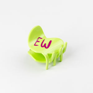 Green heart-shaped hair claw with 'EW' written on it against a white background