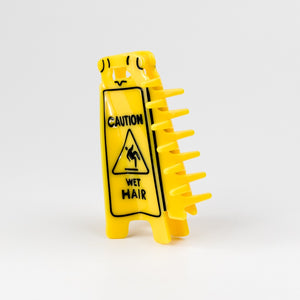 Yellow hair claw shaped like a 'Caution: Wet Hair' sign on a white background