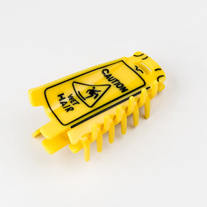 Yellow hair claw with  'Caution Wet Hair' warning label on a white background