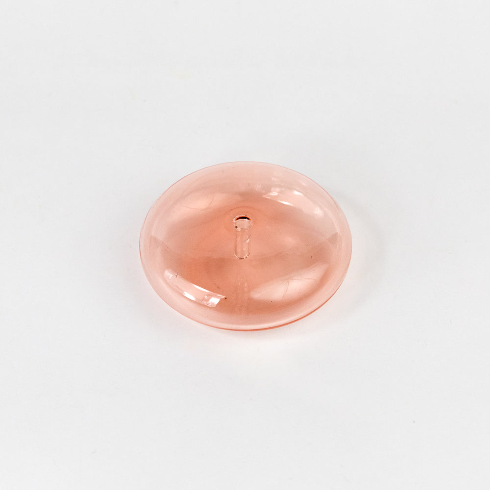 Coral colored dome-shaped incense holder on a light gray background