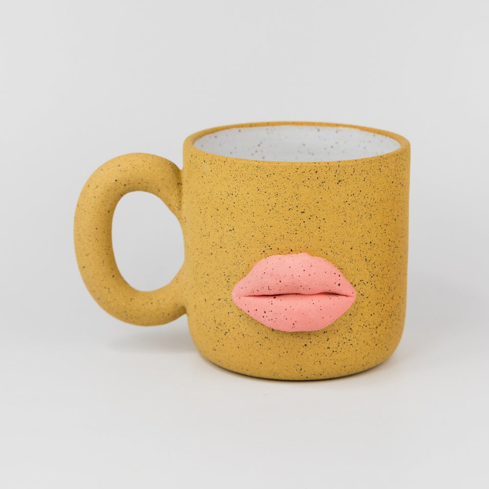 Yellow mug with pink lips on a light gray background
