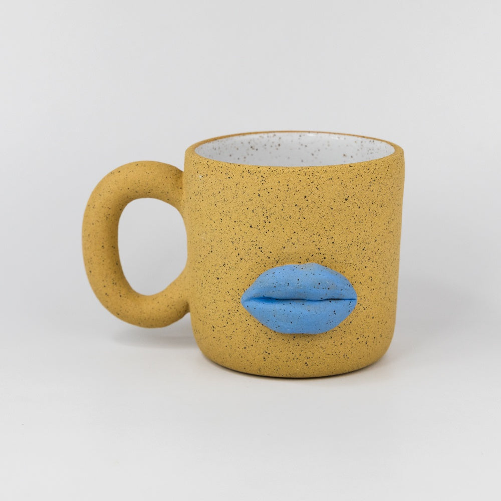 Yellow mug with blue lips on a white background