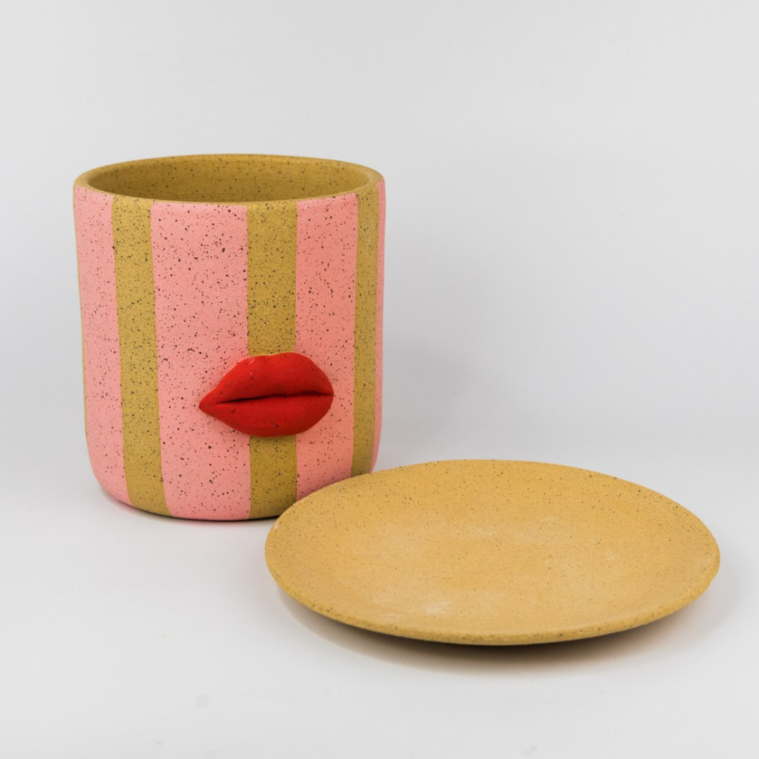 Ceramic planter with red lip design and planter dish on a white background