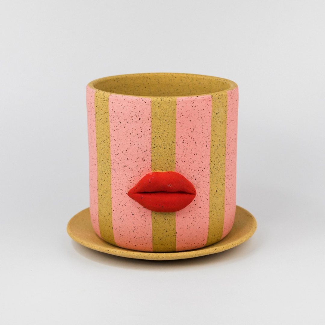 Ceramic pink striped planter with red lip design on a white background