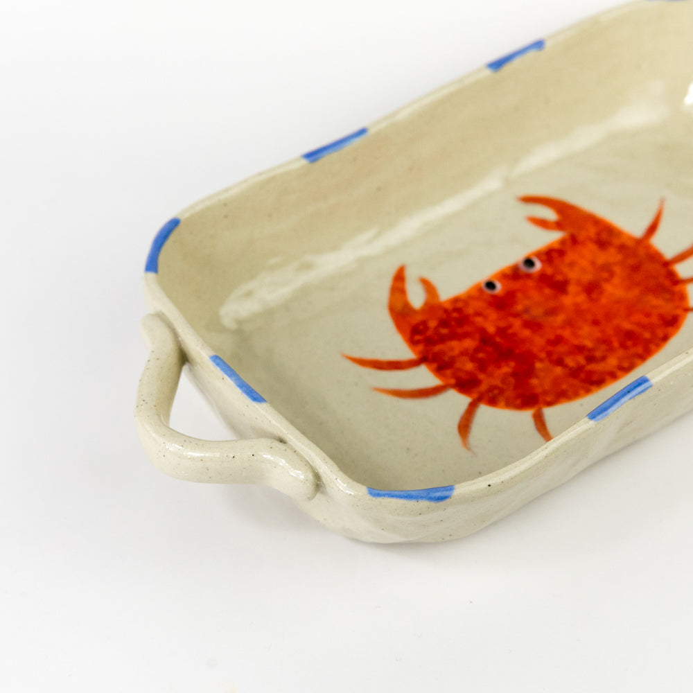 Rectangular ceramic dish with a red crab design on a beige background