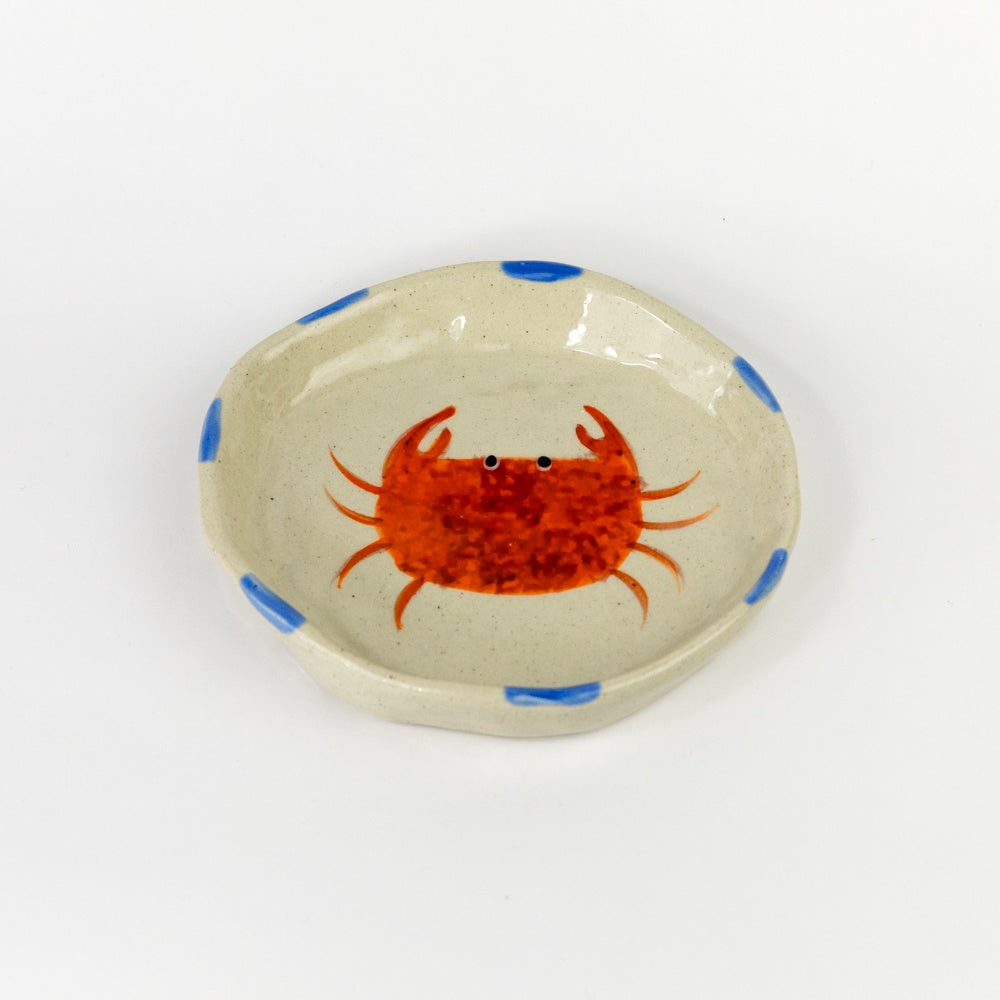 Ceramic dish with a red crab design on a beige background